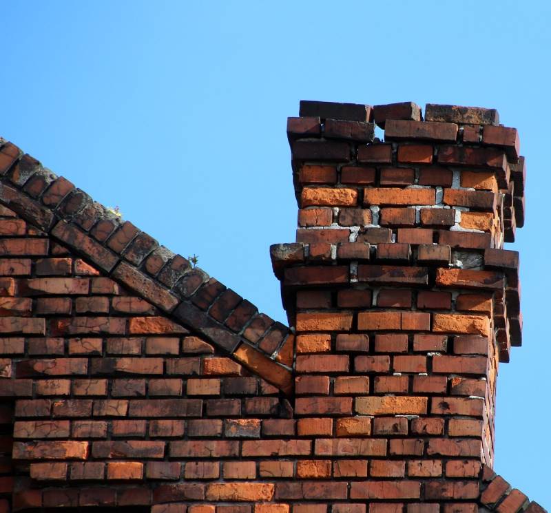 Damaged chimney on an Akron home showing cracks and missing mortar